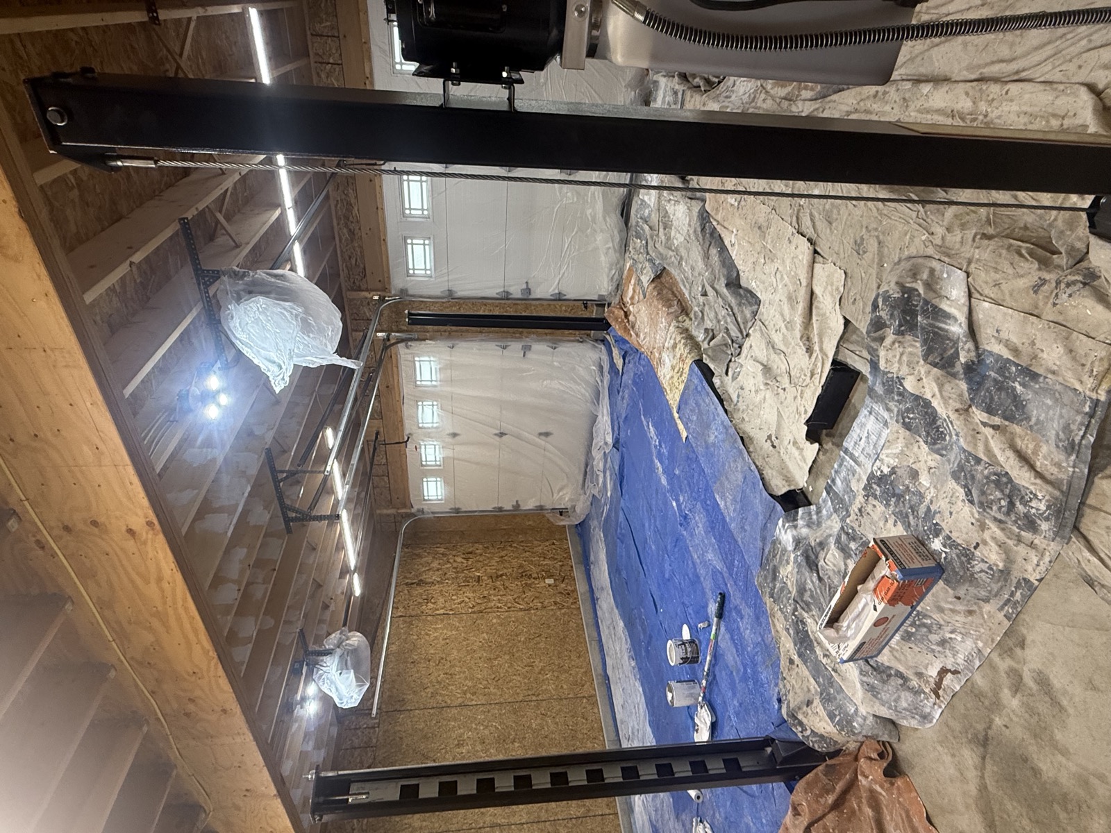 Garage painting prep with floors, doors, and equipment protected